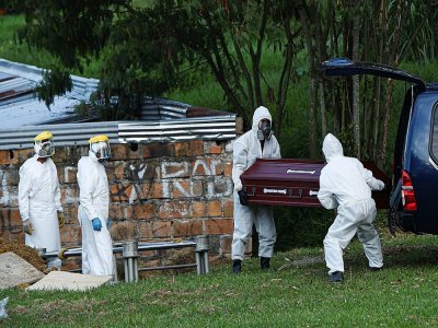 Le personnel d'un cimetière à Medellin en Colombie enterrent le cercueil d'une femme décédée du Covid-19 le 12 août 2020 - JOAQUIN SARMIENTO [AFP]