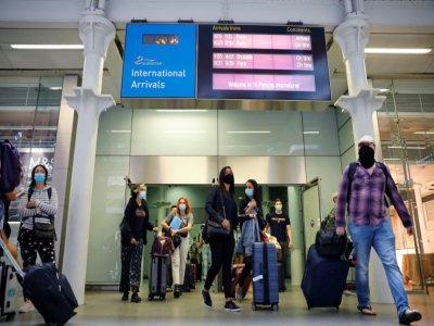 Des voyageurs portant des masques de protection dans le hall d'arrivée de la gare St Pancras, le 14 août 2020 à Londres, après avoir pris le train Eurostar à Paris - Tolga Akmen [AFP]