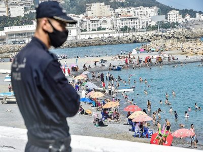 Un policier masqué surveille la plage El Kettani à Bab El Oued près d'Alger, le 15 août 2020 - RYAD KRAMDI [AFP]