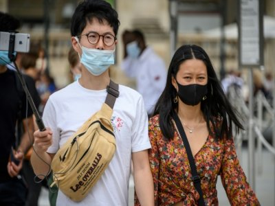 Des touristes asiatiques portent un masque de protection, le 15 août 2020 à Paris - BERTRAND GUAY [AFP]