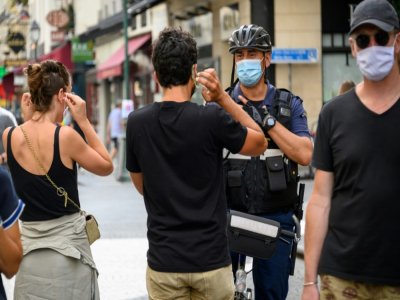 Un policier municipal demande à des passants de porter un masque de protection, le 15 août 2020 à Paris - BERTRAND GUAY [AFP]
