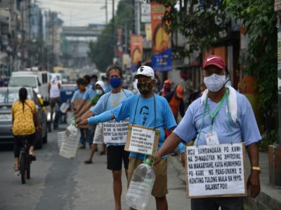Des chauffeurs de "jeepneys", mis au chômage par le confinement, mendient dans la rue, le 12 août 2020 à Manille, aux Philippines - Ted ALJIBE [AFP]