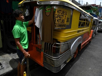 Un chauffeur de jeepney suspend ses vêtements à l'extérieur du véhicule transformé en logement, le 12 août 2020 à Manille, aux Philippines - Ted ALJIBE [AFP]