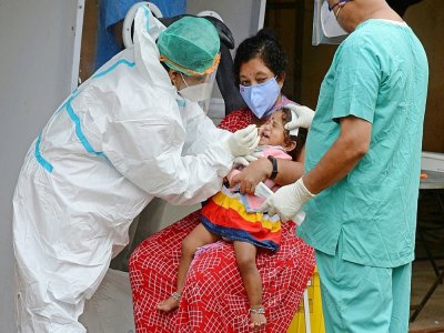 Un personnel de santé effectue un prélèvement sur une enfant dans un centre de test, le 19 août 2020 à Hyderabad, en Inde - NOAH SEELAM [AFP]