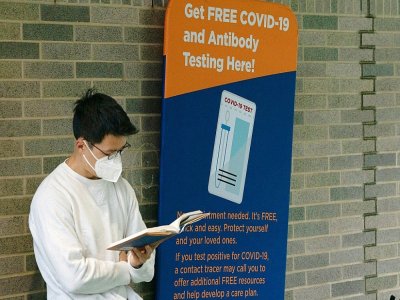 Un homme lit un livre dans la file d'attente d'un centre de dépistage du Covid-10 à l'hôpital Bellevue de New York, le 19 août 2020 - Bryan R. Smith [AFP]