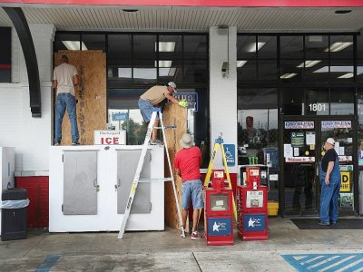 Des employés installent des panneaux en bois pour protéger les vitrines d'une boutique avant l'arrivée de l'ouragan Laura, le 25 août 2020 à Lake Charles en Louisiane - JOE RAEDLE [Getty/AFP]