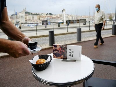 Un homme portant un masque de protection passe à côté de la terrasse d'un café sur le Vieux Port, le 2 juin 2020 à Marseille - Christophe SIMON [AFP/Archives]