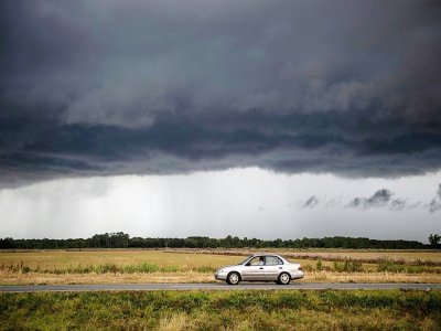 Une voiture roule sous un nuage de la tempête tropicale Marco à Lake Charles, en Louisiane, le 25 août 2020 - Andrew CABALLERO-REYNOLDS [AFP]