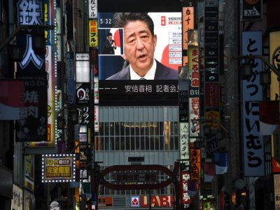 Le Premier ministre japonais Shinzo Abe, sur un grand écran retransmettant la conférence de presse dans laquelle il a annoncé son intention de démissionner, le 28 août 2020 à Tokyo - Philip FONG [AFP]