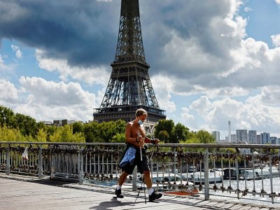 Un marcheur passe devant la tour Eiffel à Paris le 28 août 2020 - Thomas COEX [AFP]