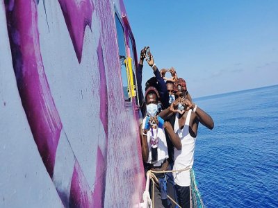 Image prise le 29 août 2020 sur le compte twitter @MVLouiseMichel. Des migrants font des coeurs avec les mains à bord du navire Banksy - - [Twitter account MVLouiseMichel/AFP]