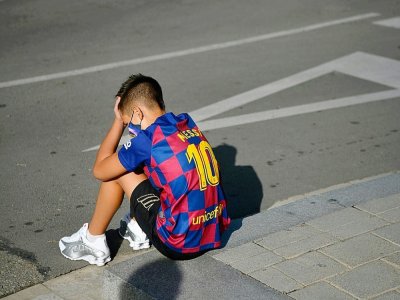 Un garçon avec le maillot de Lionel Messi attend le 30 août 2020 devant le centre d'entraînement du FC Barcelone où les joueurs devaient venir pour un dépistage du Covid - Pau BARRENA [AFP]