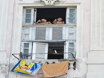 Deux enfants à une fenêtre à La Havane (Cuba) pendant un couvre-feu en raison du coronavirus le 1er septembre 2020 - YAMIL LAGE [AFP]