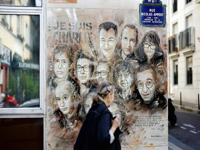 Une femme passe devant l'oeuvre de l'artiste de rue et peintre Christian Guemy, connu sous le nom de C215, en hommage aux membres de l'équipe de Charlie Hebdo assassinés en janvier 2015 par des jihadistes à Paris, le 31 août 2020 - THOMAS COEX [AFP]