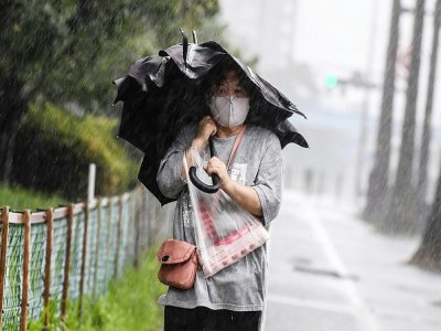 Une femme marche dans la rue à Kagoshima (Japon) alors qu'approche le typhon Haishen le 6 septembre 2020 - CHARLY TRIBALLEAU [AFP]
