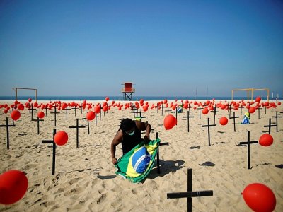 Un homme prépare une cérémonie d'hommage aux victimes du Covid-19, sur la plage de 
Copacabana à Rio de Janeiro (Brésil), le 8 août 2020 - MAURO PIMENTEL [AFP]