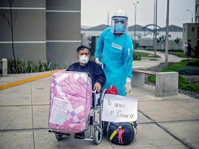 Guillermo Santos, rescapé du Covid-19, avec un membre dy personnel soignant, avant de quitter un centre de convalescence près de Lima le 28 août 2020 - ERNESTO BENAVIDES [AFP]