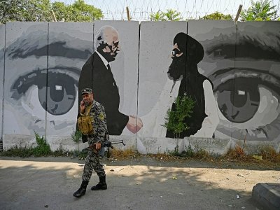 Un soldat passe devant une fresque murale dépeignant l'émissaire américain pour l'Afghanistan Zalmay Khalilzad et le co-fondateur des talibans Mullah Abdul Ghani Baradar le 31 juillet 2020 à Kaboul - WAKIL KOHSAR [AFP/Archives]