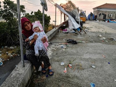 Une femme et son bébé, qui viennent de passer la nuit dans la rue, le 12 septembre 2020 sur l'île de Lesbos, en Grèce, à la suite de l'incendie du camp de migrants de Moria - LOUISA GOULIAMAKI [AFP]