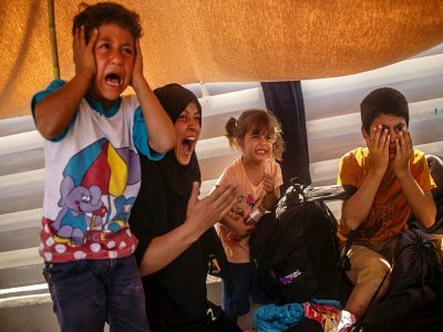 Une migrante et des enfants paniqués par des tirs de gaz lacrymogène par la police durant une manifestations de demandeurs d'asile, près de Mytilene, sur l'île grecque de Lesbos, le 12 septembre 2020 - ANGELOS TZORTZINIS [AFP]