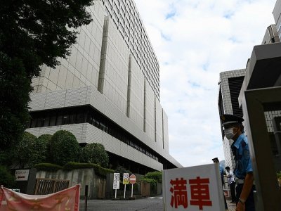 Un garde se tient devant l'entrée du tribunal où débute le procès de l'ancien directeur de Nissan, Greg Kelly, le 15 septembre 2020 à Tokyo - CHARLY TRIBALLEAU [AFP]