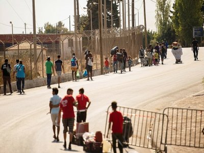 Des migrants entrent le 16 septembre dans un nouveau camp aménagé sur l'île grecque de Lesbos après l'incendie du camp de Moria - ANGELOS TZORTZINIS [AFP]