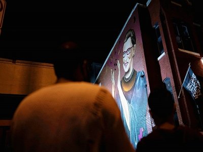 Des Américains rendent hommage à Ruth Bader Ginsburg devant une fresque murale la représentant à Washington - ALEX EDELMAN [AFP]