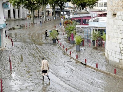 Un homme marche dans une rue d'Anduze (Gard) recouverte de boue après avoir été innondée par la rivière Gardon, en raison des pluies diluviennes qui se sont abattues sur la région, le 19 septembre 2020 - NICOLAS TUCAT [AFP]