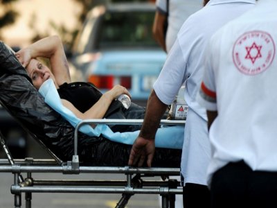 Un soignant israélien aide une rescapée de l'attaque contre un autocar touristique à Bourgas en Bulgarie à embarquer dans un vol vers un Israël le 19 juillet 2012 - NIKOLAY DOYCHINOV [AFP/Archives]