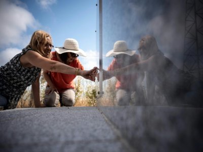 Françaises filles de Harki, les soeurs Dargaid, Rhama et Abessia (D), cherchent le nom de leurs frères sur une stèle érigée en mémoire aux personnes décédées au camp de Harki de Rivesaltes (sud de la France), le 7 août 2020 - Lionel BONAVENTURE [AFP/Archives]