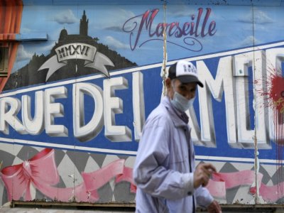 Un homme portant un masque devant un graffiti à Marseille, France, le 14 septembre 2020 - NICOLAS TUCAT [AFP/Archives]