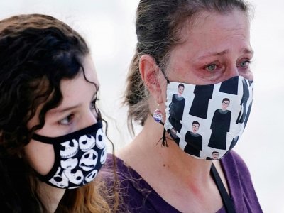 Deux femmes rendent hommage à Ruth Bader Ginsburg, dont l'une avec un masque à l'effigie de la juge défunte, à Washington, le 23 septembre 2020 - Andrew Harnik [POOL/AFP]