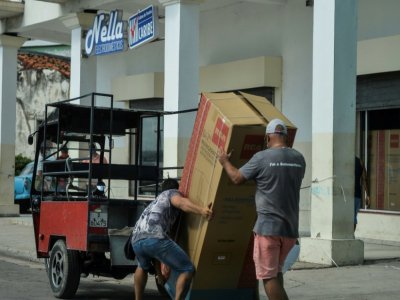 Deux hommes portent un réfrigérateur acheté dans une boutique de La Havane, le 15 septembre 2020 à Cuba - YAMIL LAGE [AFP]