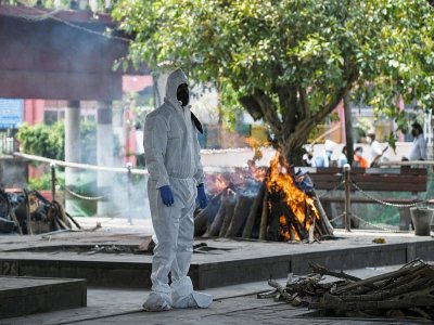 Vêtu d'une combinaison de protection, un proche d'une personne décédée du coronavirus se recueille durant la crémation, le 3 juin 2020 au Nigambodh Ghat à New Delhi - Sajjad  HUSSAIN [AFP]