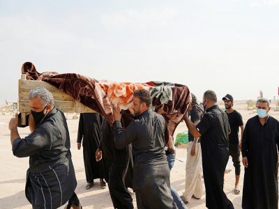 Une famille irakienne porte le cercueil d'un proche mort du coronavirus près de la ville de Najaf, le 11 septembre 2020, après la récente autorisation donnée aux familles des victimes du nouveau coronavirus de les enterrer dans les caveaux familiaux - - [AFP]