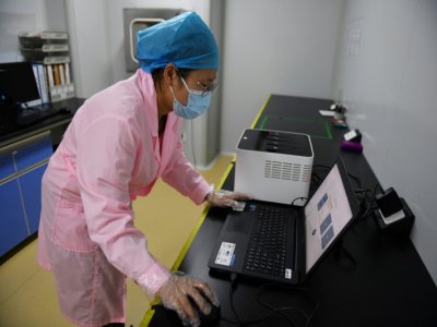Une technicienne vérifie les résultats d'un test en utilisant le Flash 20, une machine conçue par l'entreprise chinoise de biotechnologie Coyote pour réaliser des
dépistages rapides au nouveau coronavirus, le 27 septembre 2020 à Pékin - GREG BAKER [AFP]