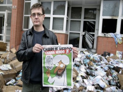 Charb brandit le 2 novembre 2011 une édition spéciale de Charlie Hebdo, après une tentative d'incendie du siège du journal à Paris. Charb sera tué dans l'attaque de janvier 2015 - ALEXANDER KLEIN [AFP/Archives]