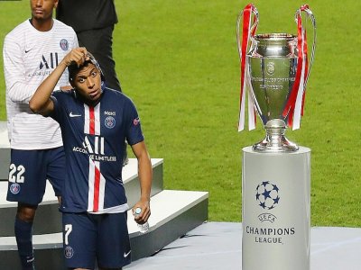 L'attaquant du Paris Saint-Germain Kylian Mbappé enlève sa médaille de finaliste en passant à côté du trophée de vainqueur de la Ligue des champions après la défaite en finale contre le Bayern Munich le 23 août 2020 à Lisbonne - Miguel A. Lopes [POOL/AFP/Archives]