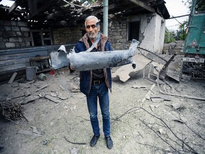 Un homme montre un fragment d'un obus tombé devant la maison de son frère dans la ville de Martuni le 1er octobre 2020. - - [AFP]