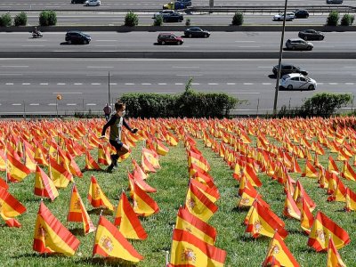 Un enfant court, le 27 septembre 2020, parmi les milliers de petits drapeaux espagnols plantés dans le parc Roma à Madrid en souvenir des victimes du Covid-19 - OSCAR DEL POZO [AFP]