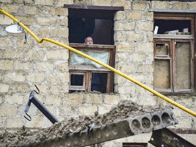 Un vieil homme regarde par une fenêtre endommagée par une explosion à Stepanakert au Nagorny Karabakh le 6 octobre 2020 - ARIS MESSINIS [AFP]