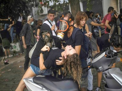 Un manifestant aide une jeune femme après des tirs de gaz lacrymogène par la police à Athènes le 7 octobre 2020 - ANGELOS TZORTZINIS [AFP]
