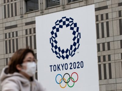 Une femme portant un masque passe devant le logo des Jeux olympiques de Tokyo, le 23 avril 2020 - Philip FONG [AFP/Archives]