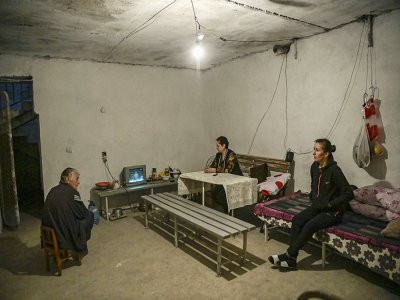 Une famille regarde la télévision dans un abri aménagé dans une cave, le 9 octobre 2020 à Martouni, dans la région disputée du Nagorny-Karabakh - ARIS MESSINIS [AFP]