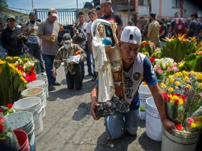 Un homme avance à genoux en tenant une statue de la Santa Muerte dans une rue du quartier de Tepito, le 1er octobre 2020 à Mexico - CLAUDIO CRUZ [AFP]