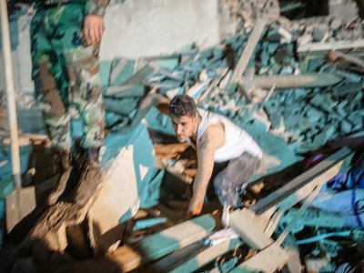 Un homme cherche parmi les débris d'une maison frappée par un missile à Gandja (Azerbaïdjan) le 17 octobre 2020 - Bulent Kilic [AFP]
