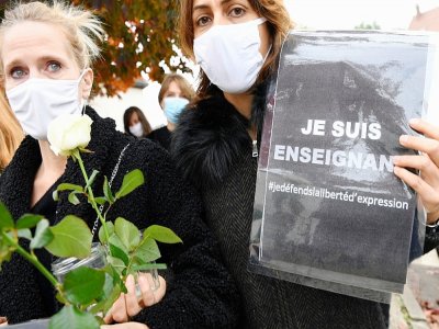Deux femmes portent des roses et des messages en faveur de la liberté d'expression le 17 octobre 2020 à Conflans-Sainte-Honorine - Bertrand GUAY [AFP]