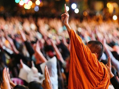 Des manifestants pro-démocratie, dont un moine bouddhiste, lèvent trois doigts en signe de résistance, le 18 octobre 2020 à Bangkok - Mladen ANTONOV [AFP]