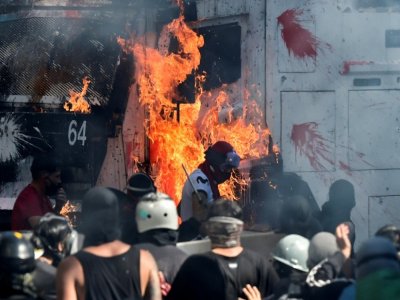 Des manifestants mettent le feu à un véhicule de police lors de la manifestation du 18 octobre 2020 à Santiago du Chili - Martin BERNETTI [AFP]