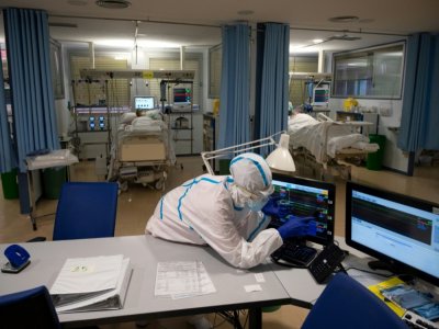 Un soignant en combinaison intégrale de protection vérifie des données sur écran d'ordinateur dans l'unité de soins intensifs de l'hôpital universitaire Severo Ochoa, le 16 octobre 2020 à Leganés, dans la banlieue de Madrid - PIERRE-PHILIPPE MARCOU [AFP]
